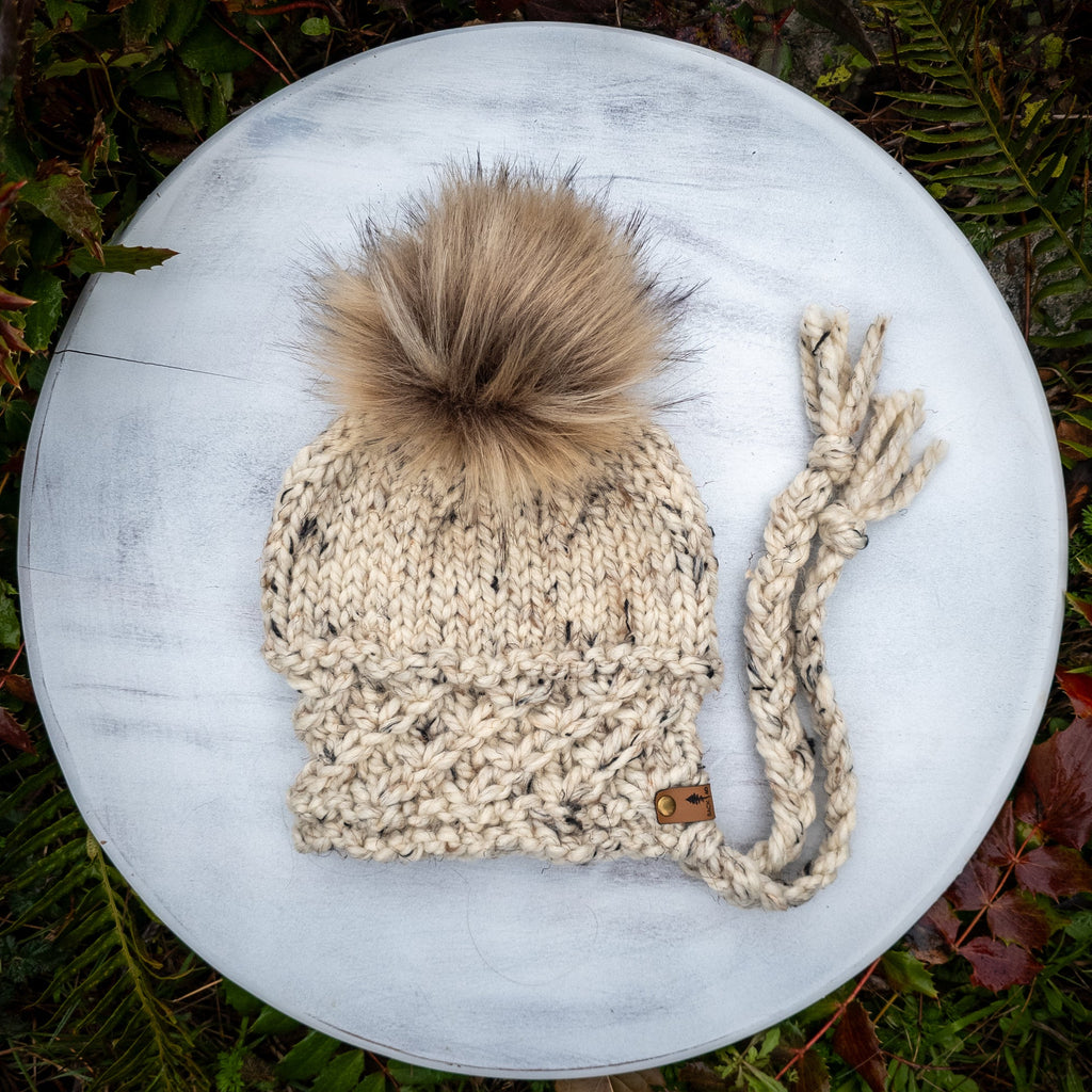 Knitted beanie with a pom-pom on a round stone surface